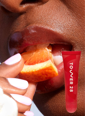[A close up of a model wearing Tower 28 Beauty's LipSoftie™ Lip Treatment in Blood-Orange Vanilla on her lips]