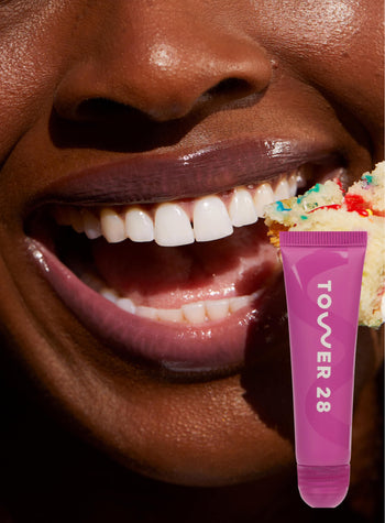 [A close up of a model wearing Tower 28 Beauty's LipSoftie™ Lip Treatment in Confetti Cake on her lips]
