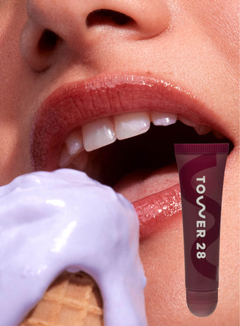 [A close up of a model wearing Tower 28 Beauty's LipSoftie™ Lip Treatment in Ube Vanilla on her lips]
